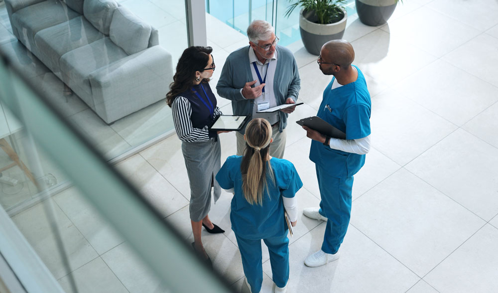 Four healthcare workers standing and meeting in lobby